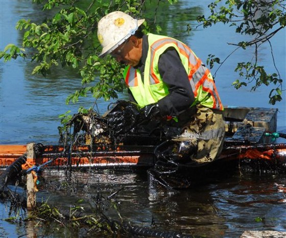 A worker lifts oil-covered debris from the Kalamazoo River in Battle Creek, Mich., on Tuesday.